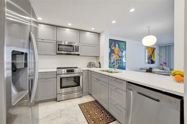 kitchen with kitchen peninsula, gray cabinetry, stainless steel appliances, sink, and hanging light fixtures