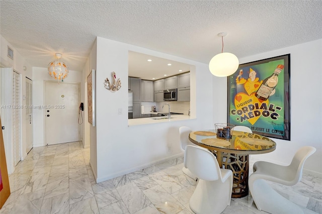 dining area featuring sink and a textured ceiling