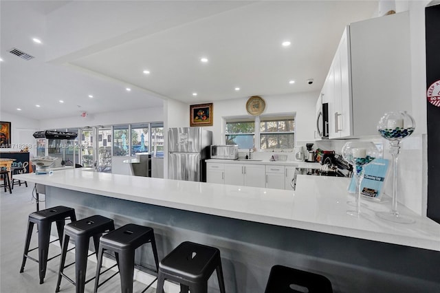 kitchen with white cabinets, a kitchen breakfast bar, sink, kitchen peninsula, and stainless steel appliances