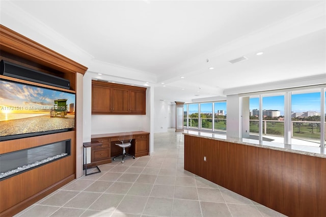 kitchen featuring light stone countertops, light tile patterned floors, built in desk, and crown molding