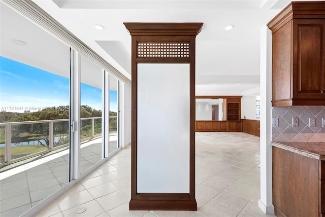 corridor featuring light tile patterned floors and a water view