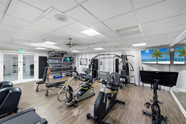 exercise room featuring a paneled ceiling, ceiling fan, hardwood / wood-style flooring, and french doors