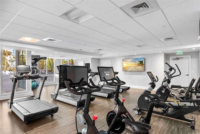 workout area with a paneled ceiling and wood-type flooring