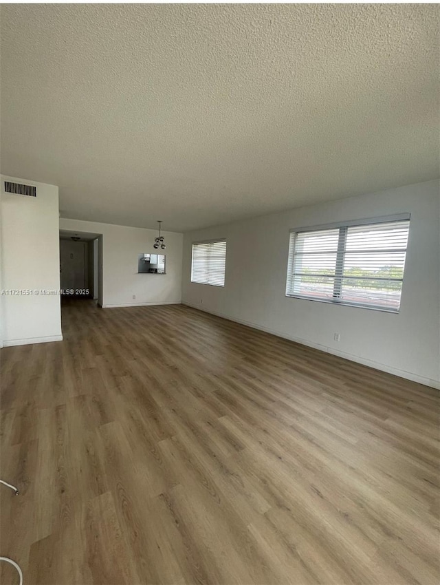 unfurnished living room with hardwood / wood-style floors and a textured ceiling