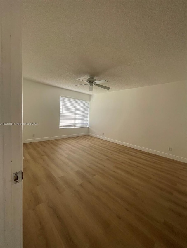 empty room with ceiling fan, hardwood / wood-style floors, and a textured ceiling