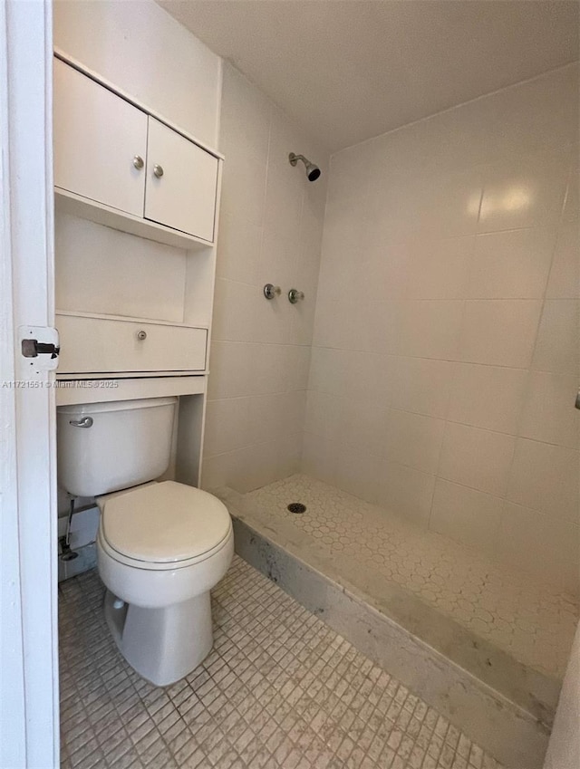 bathroom featuring a tile shower and toilet