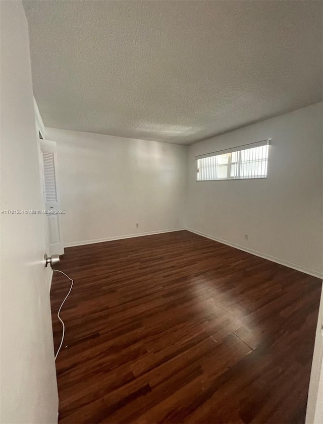 spare room with a textured ceiling and dark hardwood / wood-style floors