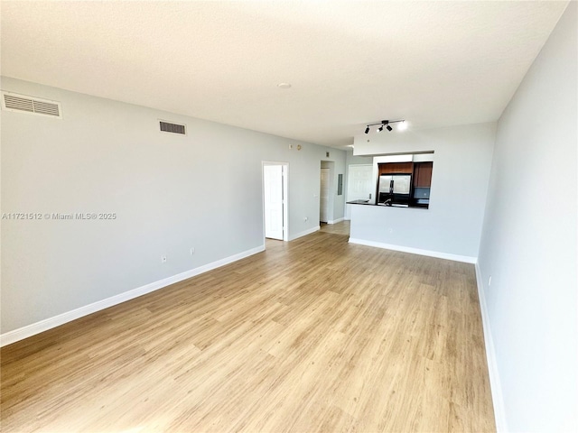 unfurnished living room with visible vents, baseboards, and light wood finished floors