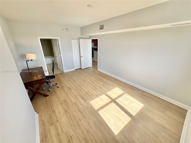 office space with light wood-style flooring, visible vents, and baseboards