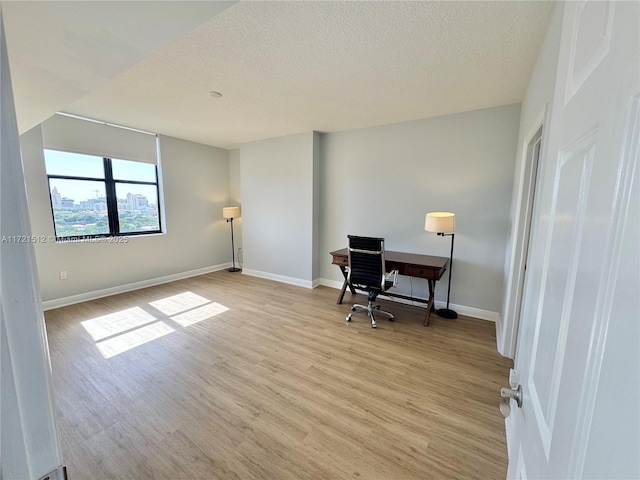 office featuring baseboards, a textured ceiling, and light wood-style flooring