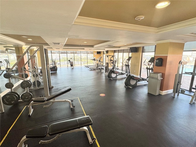 workout area featuring a tray ceiling and ornamental molding