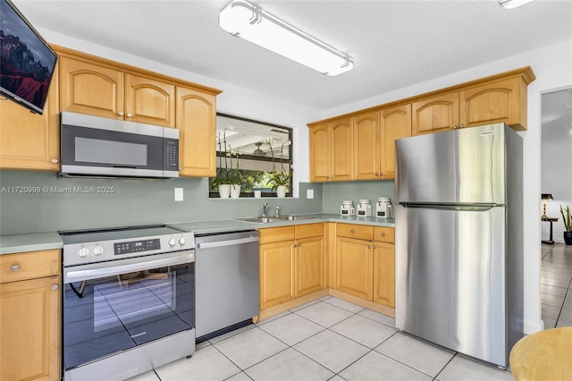 kitchen featuring light tile patterned floors, appliances with stainless steel finishes, light countertops, and a sink