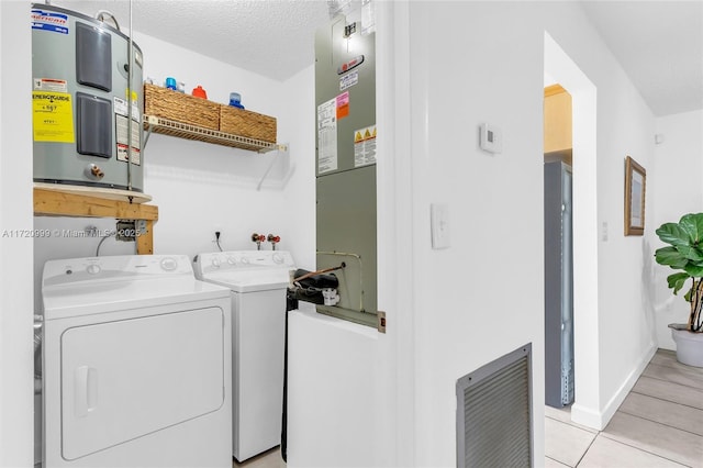 laundry room featuring water heater, light tile patterned flooring, a textured ceiling, separate washer and dryer, and laundry area