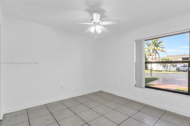 empty room featuring light tile patterned floors, ceiling fan, and baseboards