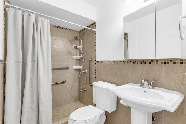 bathroom featuring a wainscoted wall, tile walls, toilet, a sink, and a shower stall