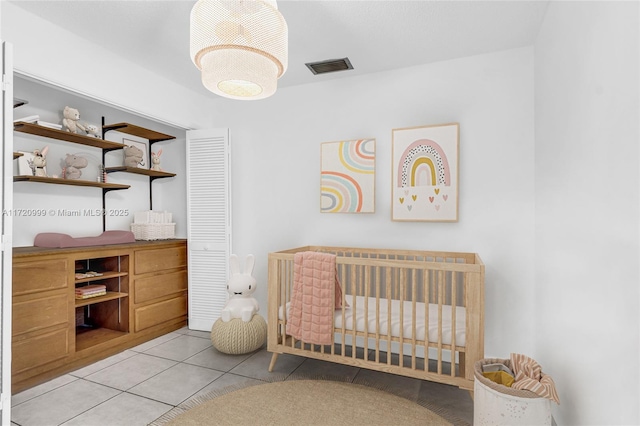 bedroom with light tile patterned floors, a crib, and visible vents