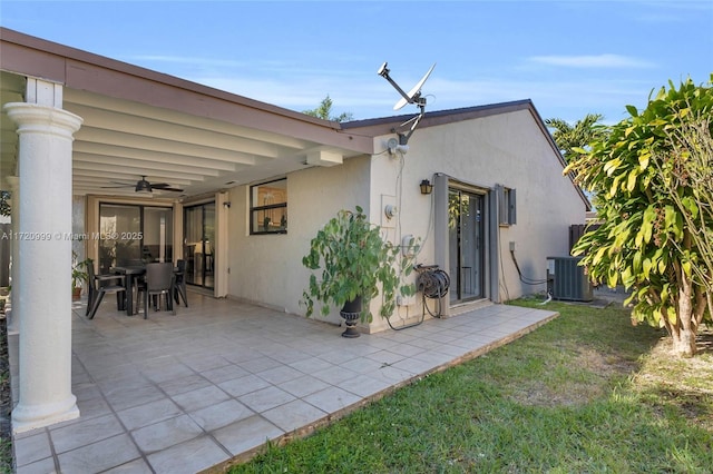 back of house with central AC unit, a ceiling fan, a patio, outdoor dining area, and stucco siding