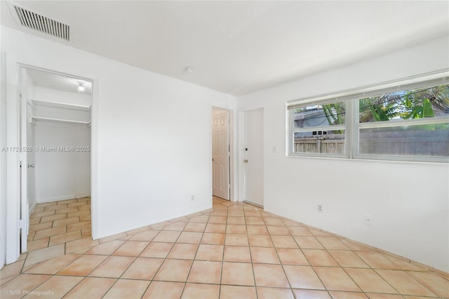 unfurnished bedroom with a spacious closet, a closet, and light tile patterned floors