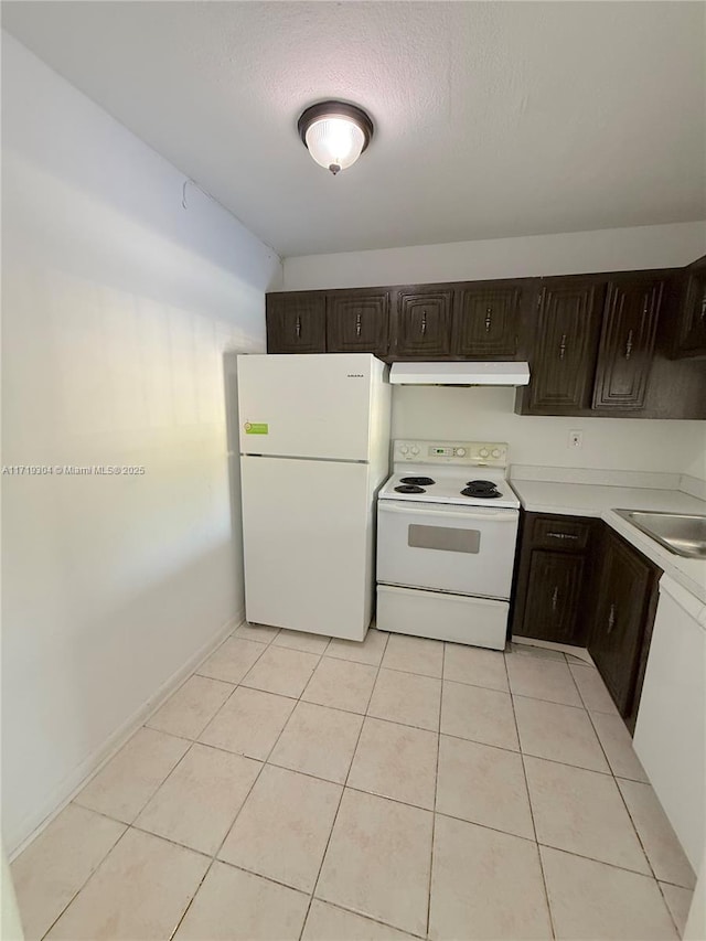 kitchen featuring dark brown cabinetry, under cabinet range hood, white appliances, a sink, and light countertops