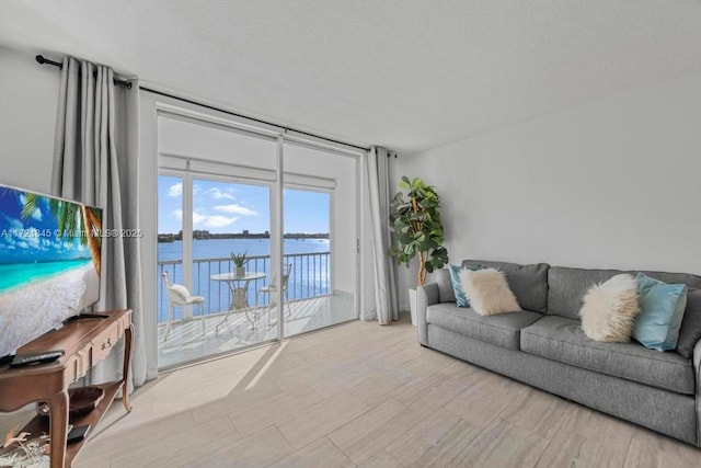 living room with floor to ceiling windows, a water view, and a textured ceiling