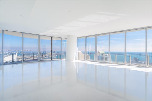 tiled empty room featuring expansive windows and a water view