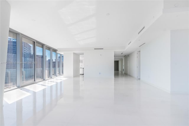 tiled spare room with expansive windows and a healthy amount of sunlight