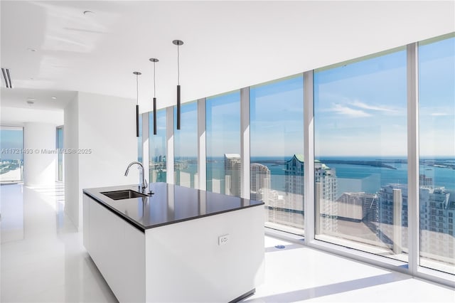 kitchen with white cabinets, a wall of windows, sink, and hanging light fixtures