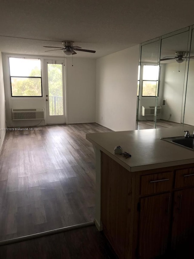 kitchen featuring an AC wall unit, ceiling fan, sink, and hardwood / wood-style flooring