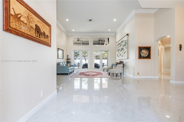 hallway with french doors, a towering ceiling, and ornamental molding