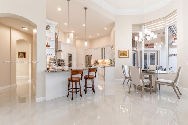 kitchen with light stone countertops, kitchen peninsula, pendant lighting, white cabinets, and appliances with stainless steel finishes