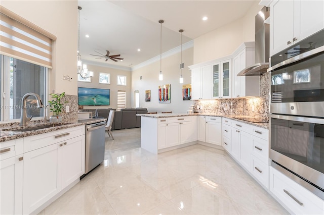 kitchen featuring white cabinets, stainless steel appliances, light stone countertops, and wall chimney range hood