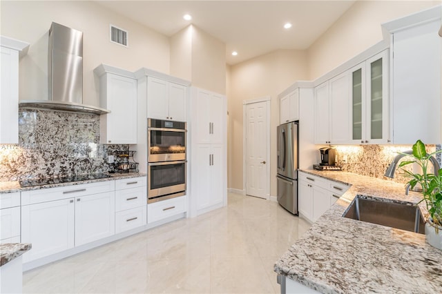 kitchen with white cabinetry, sink, stainless steel appliances, wall chimney range hood, and decorative backsplash