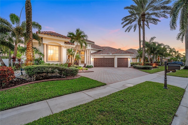 mediterranean / spanish-style home featuring a garage and a lawn