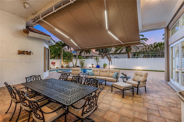 patio terrace at dusk with outdoor lounge area and a fenced in pool