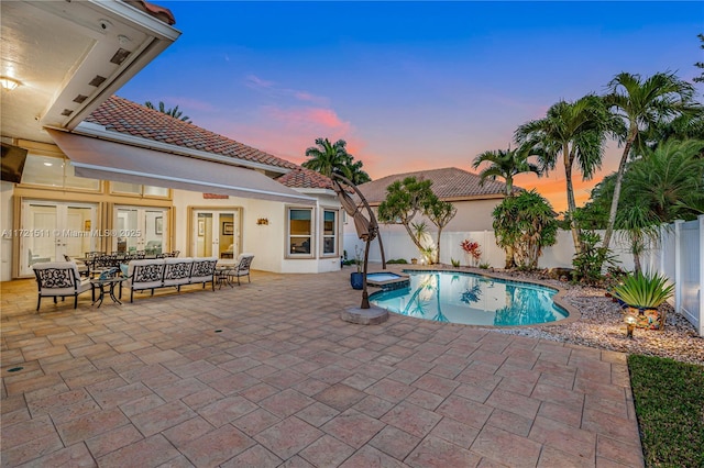 pool at dusk with an in ground hot tub, french doors, a patio area, and outdoor lounge area