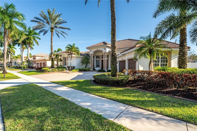 mediterranean / spanish home featuring a front yard and a garage