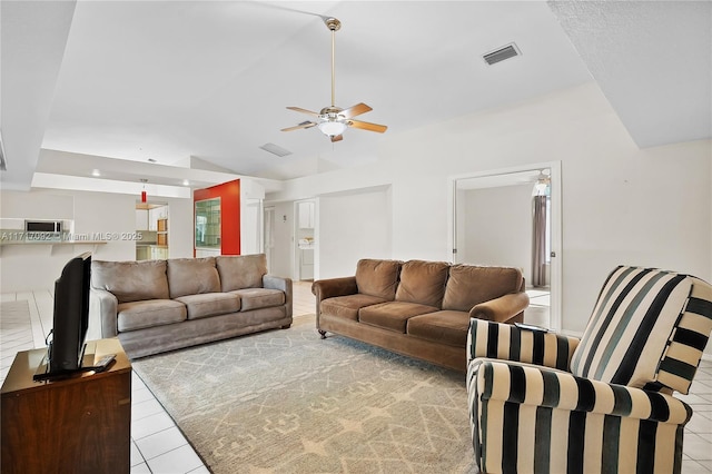 living room with ceiling fan, lofted ceiling, and light tile patterned flooring