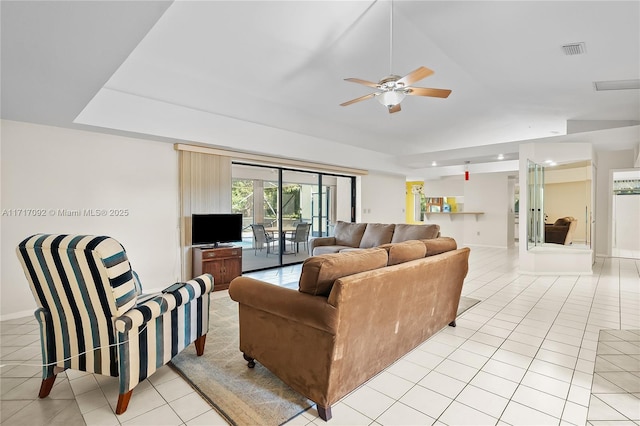 tiled living room with a tray ceiling and ceiling fan