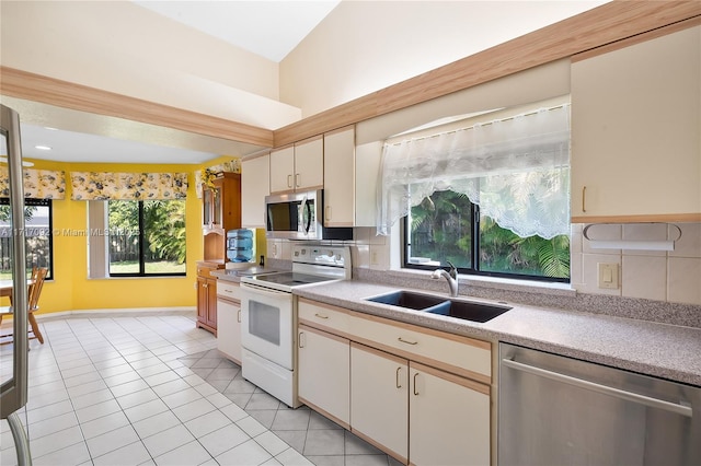 kitchen with light tile patterned floors, stainless steel appliances, a wealth of natural light, and sink