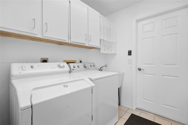 clothes washing area featuring cabinets, washer and clothes dryer, and light tile patterned flooring