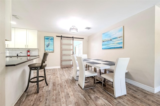 dining area with light wood-type flooring and a barn door