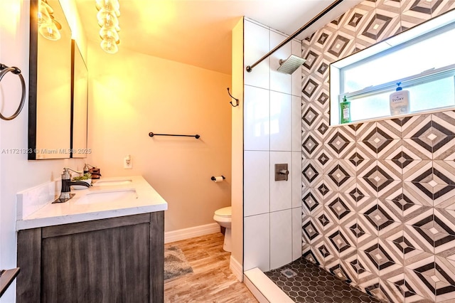 bathroom with toilet, vanity, hardwood / wood-style floors, and tiled shower
