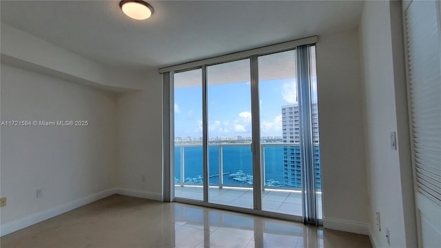 tiled empty room featuring floor to ceiling windows and a water view