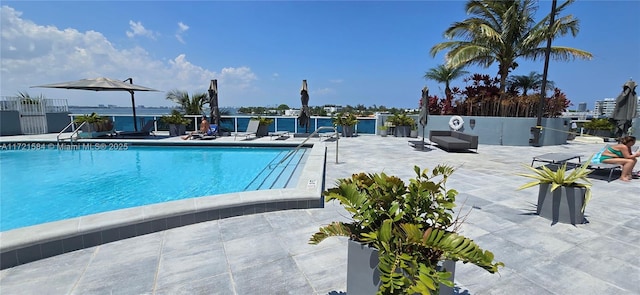 view of swimming pool featuring a patio area and a water view