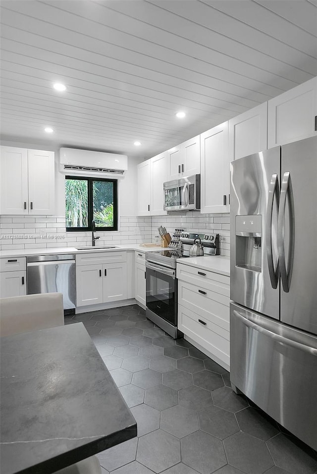 kitchen with an AC wall unit, sink, white cabinets, and appliances with stainless steel finishes