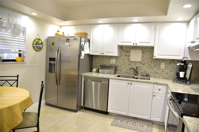 kitchen featuring sink, appliances with stainless steel finishes, backsplash, light stone countertops, and white cabinets