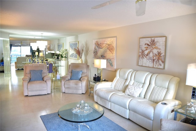 living room featuring ceiling fan and a textured ceiling