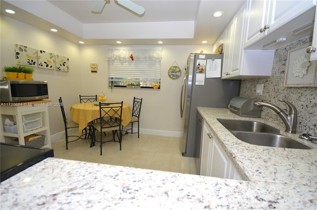 kitchen featuring sink, light stone counters, appliances with stainless steel finishes, white cabinets, and backsplash