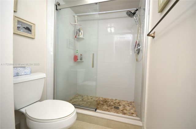 bathroom featuring toilet and a shower with door