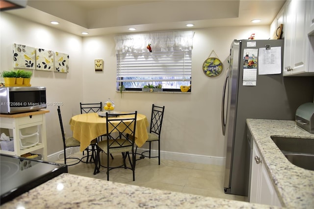 kitchen featuring white cabinetry, light stone countertops, sink, and light tile patterned flooring